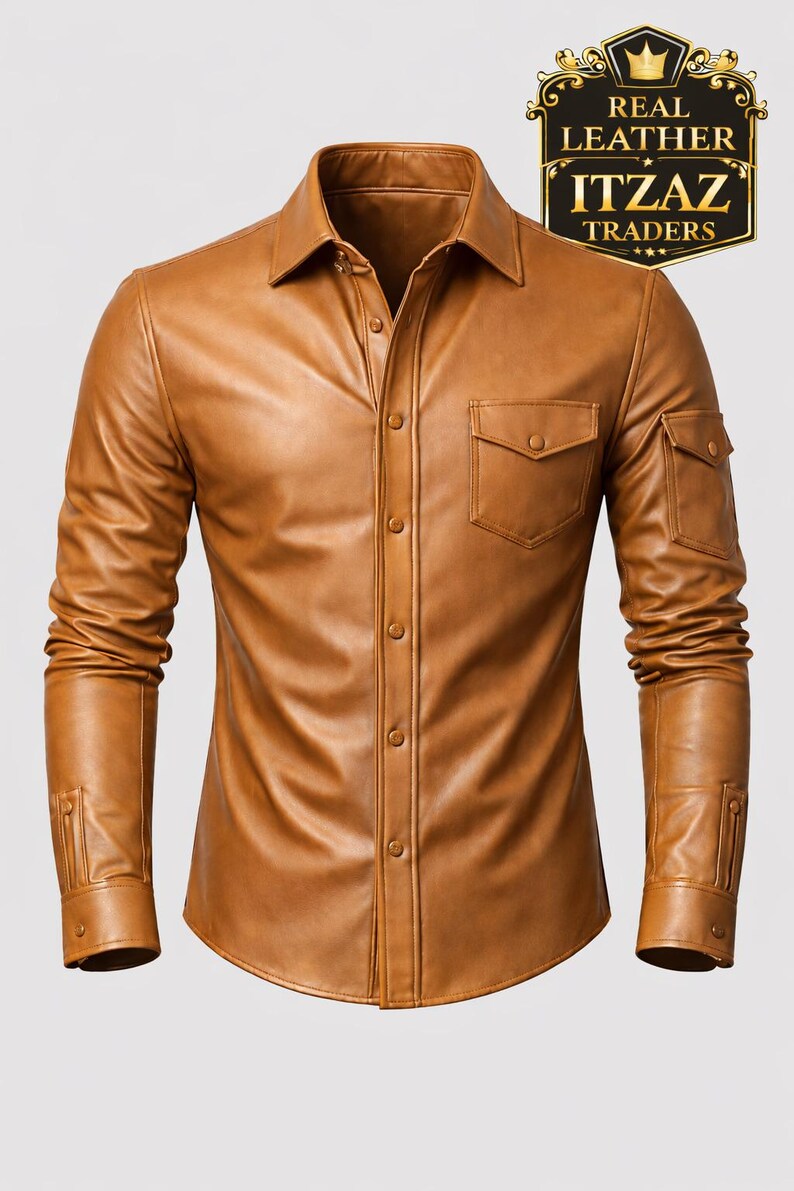 Op de afbeelding: Een bruin leren overhemd met een knoopsluiting, twee borstzakken en twee mouwzakken. Het overhemd heeft lange mouwen en een kraag. De afbeelding bevat een zwart en goud logo met de tekst "REAL LEATHER ITZAZ TRADERS."