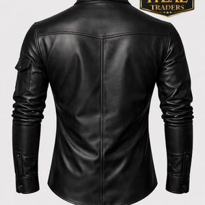 Op de afbeelding: Zwart leren overhemd met een klassieke kraag, lange mouwen en een klein zakje op de linkermouw. Het overhemd heeft een knoopsluiting en een getailleerde pasvorm. Het logo "REAL LEATHER ITZAZ TRADERS" is zichtbaar.