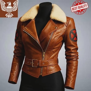 Può includere: Giacca in pelle marrone con collo in pelliccia color crema, cerniera frontale e cintura. La giacca ha una toppa rotonda con una X rossa sulla manica sinistra. La giacca è esposta su un manichino nero.