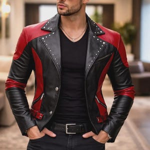 Könnte beinhalten: Schwarze Lederjacke mit roten Schulter- und Ärmelakzenten. Die Jacke hat einen Nietenkragen, Reißverschlusstaschen und einen Gürtel. Das Model trägt eine schwarze Jeans und eine Sonnenbrille. Ein stilvolles und kantiges Oberbekleidungsstück.