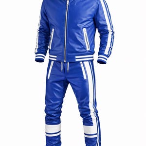 Pode incluir: Fato de treino de couro azul com riscas brancas. O casaco tem fecho de correr e dois bolsos laterais. As cal&ccedil;as t&ecirc;m cintura com cord&atilde;o e riscas brancas nas laterais. A marca "Itzaztraders" &eacute; vis&iacute;vel no canto superior esquerdo.