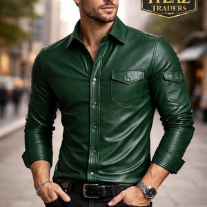Op de afbeelding: Een donkergroen leren overhemd met twee borstzakken en knopen. Het overhemd wordt gecombineerd met een zwarte broek en een zwarte riem. De afbeelding bevat de tekst "REAL LEATHER ITZAZ TRADERS".