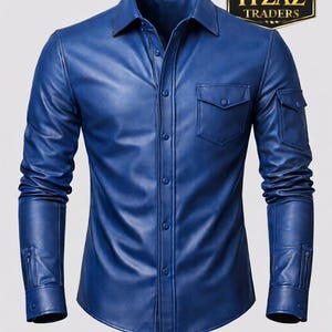 Op de afbeelding: Een blauw leren overhemd met een knoopsluiting, een borstzak en een mouwzak. Het overhemd heeft lange mouwen en een klassieke kraag. De afbeelding bevat een logo met de tekst "REAL LEATHER ITZAZ TRADERS".