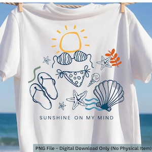 Könnte beinhalten: Weißes T-Shirt mit einem Strandmotiv. Das Design umfasst eine Sonne, einen Bikini, Flip-Flops, Seesterne, ein Eis und eine Muschel. Der Text "SUNSHINE ON MY MIND" ist darunter gedruckt. Das T-Shirt hängt an einer Wäscheleine.