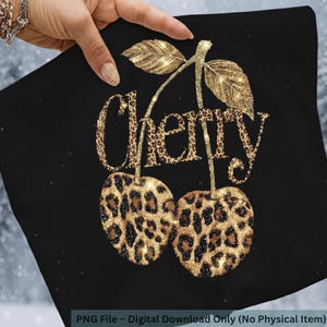 Puede incluir: Cuadrado negro con un dise&ntilde;o de cereza con purpurina dorada. La palabra "Cherry" est&aacute; escrita en purpurina dorada con un estampado de leopardo. Las cerezas tambi&eacute;n tienen un estampado de leopardo.