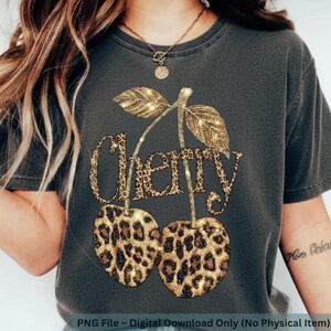 Puede incluir: Camiseta gris oscuro con un dise&ntilde;o de cereza con purpurina dorada y estampado de leopardo. La palabra "Cherry" est&aacute; escrita en una fuente con purpurina dorada y estampado de leopardo. La camiseta es una descarga digital.