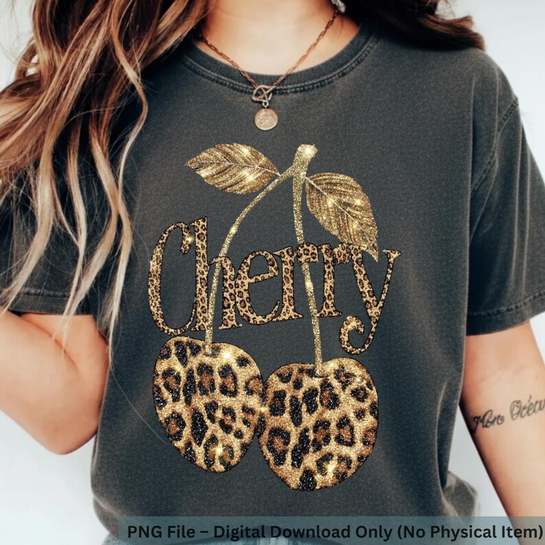 Puede incluir: Camiseta gris oscuro con un dise&ntilde;o de cereza con purpurina dorada y estampado de leopardo. La palabra "Cherry" est&aacute; escrita en una fuente con purpurina dorada y estampado de leopardo. La camiseta es una descarga digital.