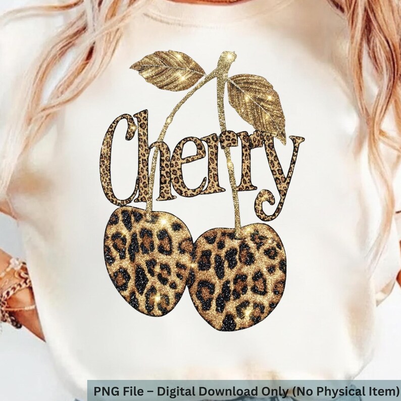 Puede incluir: Camiseta blanca con un dise&ntilde;o de estampado de leopardo brillante de dos cerezas y la palabra "Cherry". Las cerezas y el texto tienen un efecto de brillo dorado. El dise&ntilde;o incluye hojas y tallos dorados brillantes.