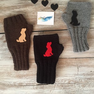 May include: Three pairs of knitted fingerless gloves with a dog silhouette design. The gloves are brown, black, and gray. The dog silhouettes are beige, red, and black.