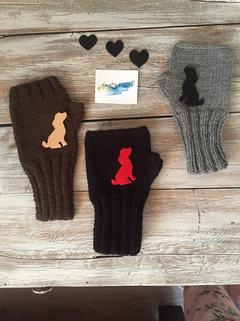 May include: Three pairs of knitted fingerless gloves with a dog silhouette design. The gloves are brown, black, and gray. The dog silhouettes are beige, red, and black.