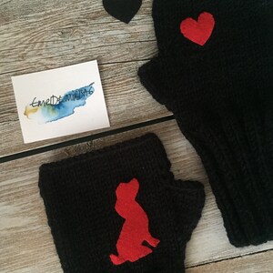 May include: Two black fingerless gloves with red felt appliques. One glove has a heart shape and the other has a dog silhouette.