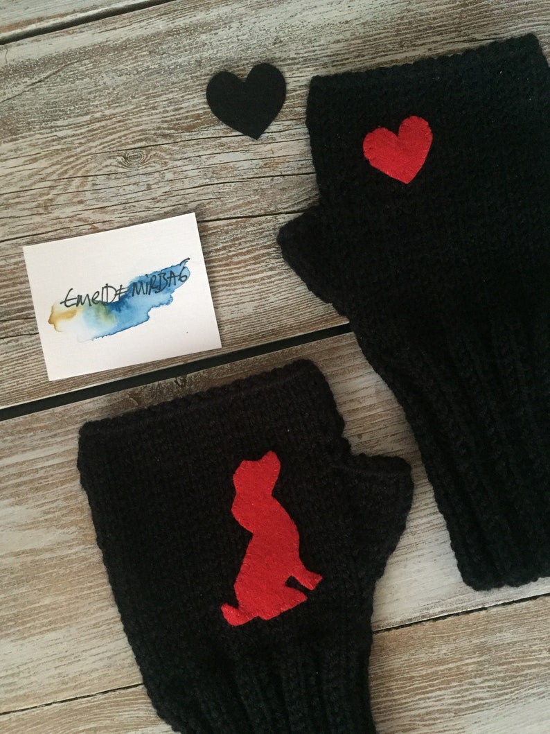 May include: Two black fingerless gloves with red felt appliques. One glove has a heart shape and the other has a dog silhouette.