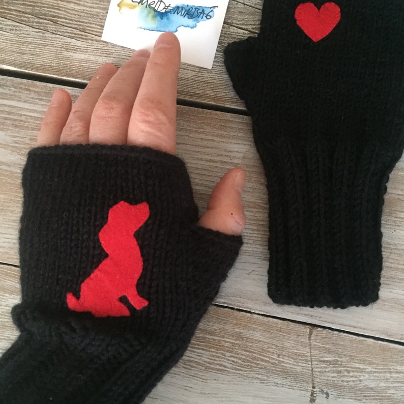 May include: Pair of black fingerless gloves with red felt appliques. One glove has a heart shape and the other has a dog silhouette.