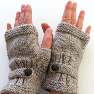 May include: A pair of gray fingerless gloves with a button detail. The gloves are knitted and have a ribbed cuff.
