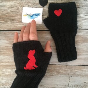 May include: A pair of black fingerless gloves with red felt appliques. One glove has a heart shape and the other has a dog silhouette.