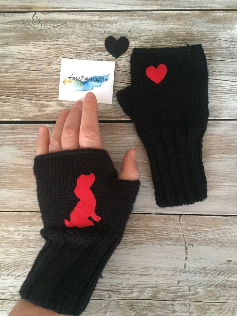 May include: A pair of black fingerless gloves with red felt appliques. One glove has a heart shape and the other has a dog silhouette.