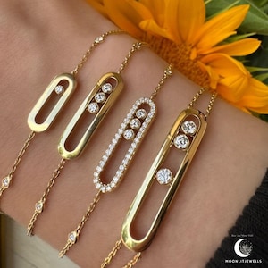 Könnte beinhalten: Gezeigt werden vier goldene Armbänder mit Diamantakzenten. Jedes Armband hat ein einzigartiges Design, mit oval geformten Mittelstücken, die eine unterschiedliche Anzahl von Diamanten halten. Die Armbänder sind durch zarte Goldketten verbunden, die eine luxuriöse Schmuckkollektion präsentieren.