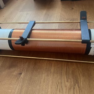 May include: A handmade radio coil with copper wire wrapped around a white cylinder. The coil is held in place by black supports and brass rods. The device is designed for radio frequency applications.