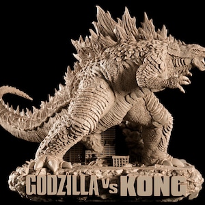 Könnte beinhalten: Beige Skulptur von Godzilla in dynamischer Pose, mit dem Text "GODZILLA vs KONG" auf dem Sockel. Die Figur hat strukturierte Haut, Rückenflossen und eine detaillierte Stadtlandschaft. Die Skulptur steht vor einem schwarzen Hintergrund.