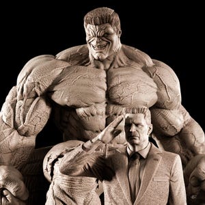 Può includere: Una scultura in seppia con due figure. La figura più grande, un personaggio muscoloso dalla pelle verde, incombe su un uomo in giacca e cravatta che saluta. La figura simile a Hulk ha un sorriso minaccioso. L'uomo in giacca ha un'espressione severa.
