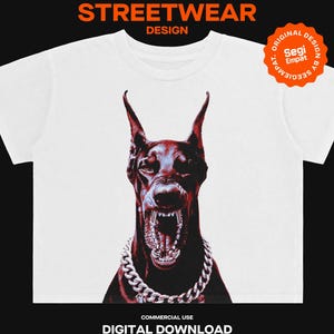 May include: A white t-shirt featuring a graphic of a snarling Doberman dog wearing a thick silver chain necklace. The text Y2K STREETWEAR DESIGN appears at the top, with a circular orange badge reading ORIGINAL DESIGN BY SEGI EMPAT.