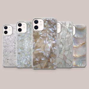 May include: Five iridescent phone cases with various shell-like designs. The cases feature a range of colors, including white, beige, and pearlescent hues. The designs include mosaic, scale, and natural shell patterns, offering a stylish and protective accessory.