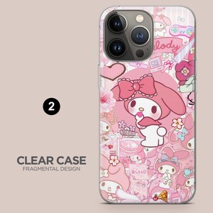 May include: Clear phone case with a pink fragmented design. The case features a cartoon character with a pink bow, surrounded by hearts, flowers, and other cute illustrations. The text "CLEAR CASE FRAGMENTAL DESIGN" is visible.