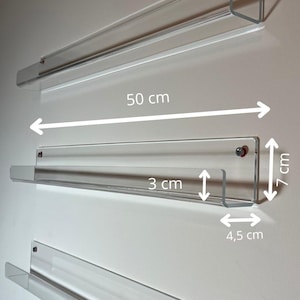 Op de afbeelding: Transparante acryl wandplanken, elk 50 cm lang, 7 cm hoog en 4,5 cm diep. De planken worden bevestigd met kleine schroeven met rode doppen. De voorrand van de plank is 3 cm.
