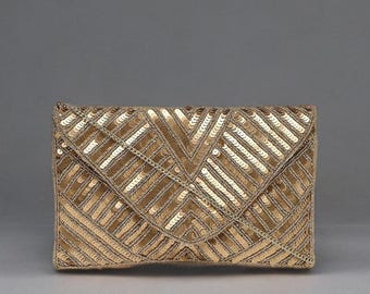 May include: A gold sequined clutch with a geometric pattern. The rectangular bag has a flap closure and a chain strap. The sequins are arranged in a chevron design, creating a shimmering effect. The clutch is a stylish accessory for special occasions.