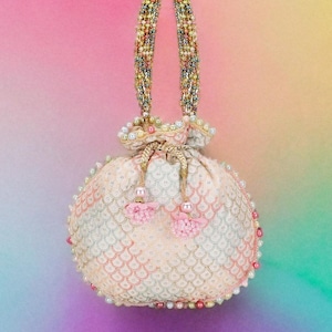 May include: A cream-coloured beaded handbag with a drawstring closure. The bag has a scale-like pattern and is decorated with pearls and pink tassels. The handles are embellished with colourful beads.