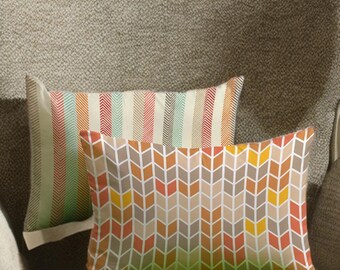 May include: Two decorative throw pillows with colorful geometric patterns. One pillow features vertical stripes in shades of red, orange, green, and beige. The other pillow has a chevron design in orange, yellow, and gray.
