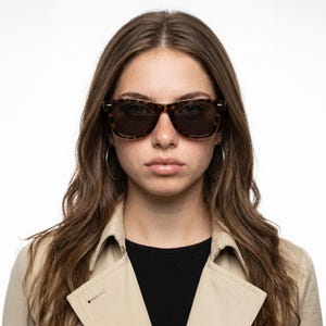 May include: Tortoiseshell sunglasses with dark, tinted lenses and a classic wayfarer-style frame. The frames feature a mottled brown and black pattern, providing a distinct contrast against the dark lenses. The design includes silver-tone accents.