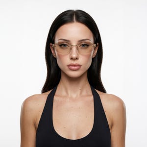 May include: Rimless oval eyeglasses featuring light brown tinted lenses and a thin gold-tone metal frame. The bridge and temples are constructed from slender gold metal, providing a lightweight appearance with a classic oval lens shape.
