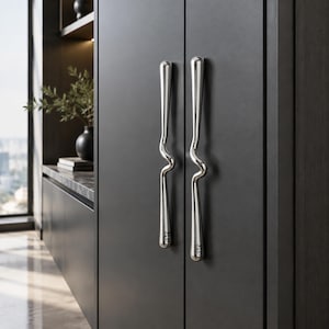 May include: Two vertical, polished chrome cabinet handles with a distinct, central wavy curve, mounted on a matte dark gray cabinet door. The metal hardware features a smooth, reflective finish and a slender, elongated shape that contrasts with the dark surface.