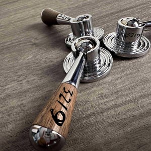 Op de afbeelding: Drie metalen kraangrepen met een gepolijste chromen afwerking en houten accenten. Elke greep heeft een ronde basis met concentrische ringen en een hendel. Het nummer 3219 staat duidelijk vermeld op de houten greep en de chromen onderdelen.