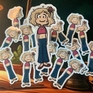May include: A collection of stickers featuring a cartoon character with blonde curly hair, a pink crop top, and blue jeans. The character has a flower in their hair and a smiling expression. The stickers are on a dark background.