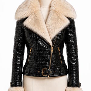 Könnte beinhalten: Eine schwarze Jacke mit glänzender Krokodilprägung, ausgestattet mit einem großen cremefarbenen Kunstfellkragen und passenden Kunstfellbündchen. Die Jacke verfügt über goldfarbene Reißverschlüsse an der Vorderseite und den Taschen sowie einen Gürtel.