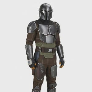 Peut inclure: Vue d'ensemble d'un costume de Mandalorien. Le costume comprend un casque argenté, une armure de poitrine et divers éléments bruns et gris. La tenue comprend un col roulé foncé, des gants et des bottes. Le design est détaillé et réaliste.