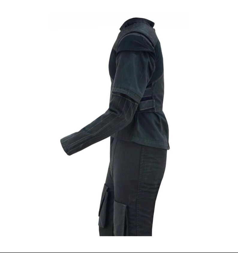 Peut inclure: Tenue noire compos&eacute;e d'une veste et d'un pantalon. La veste pr&eacute;sente des &eacute;paules structur&eacute;es, une taille ajust&eacute;e et un col montant. Les manches longues sont ray&eacute;es. Le pantalon a des poches cargo. L'ensemble est en mati&egrave;re sombre, possiblement denim.