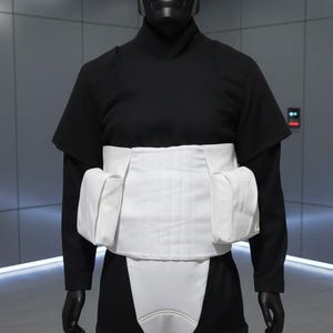 May include: A black futuristic helmet and uniform with a white waist and chest piece. The helmet has a visor and ear pieces. The uniform is black with a high collar and short sleeves. The waist piece has two pockets.