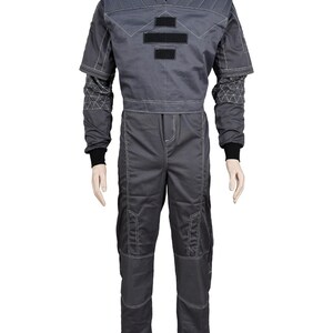 May include: A gray jumpsuit with a quilted upper section and contrasting white stitching. The suit features black accents and a high collar. The sleeves have a geometric pattern near the wrists, and the pants have reinforced knee patches. The overall design suggests a futuristic or tactical aesthetic.