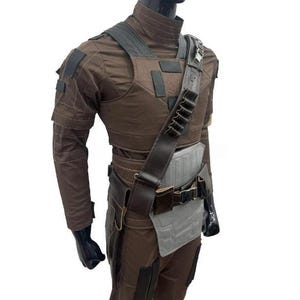 May include: Brown tactical costume with a vest, shoulder strap, and belt. The costume features multiple pockets and patches. The mannequin is wearing a brown long-sleeve shirt and trousers. The costume is designed for cosplay or costume parties.