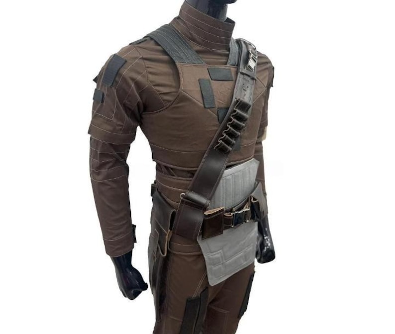 May include: Brown tactical costume with a vest, shoulder strap, and belt. The costume features multiple pockets and patches. The mannequin is wearing a brown long-sleeve shirt and trousers. The costume is designed for cosplay or costume parties.