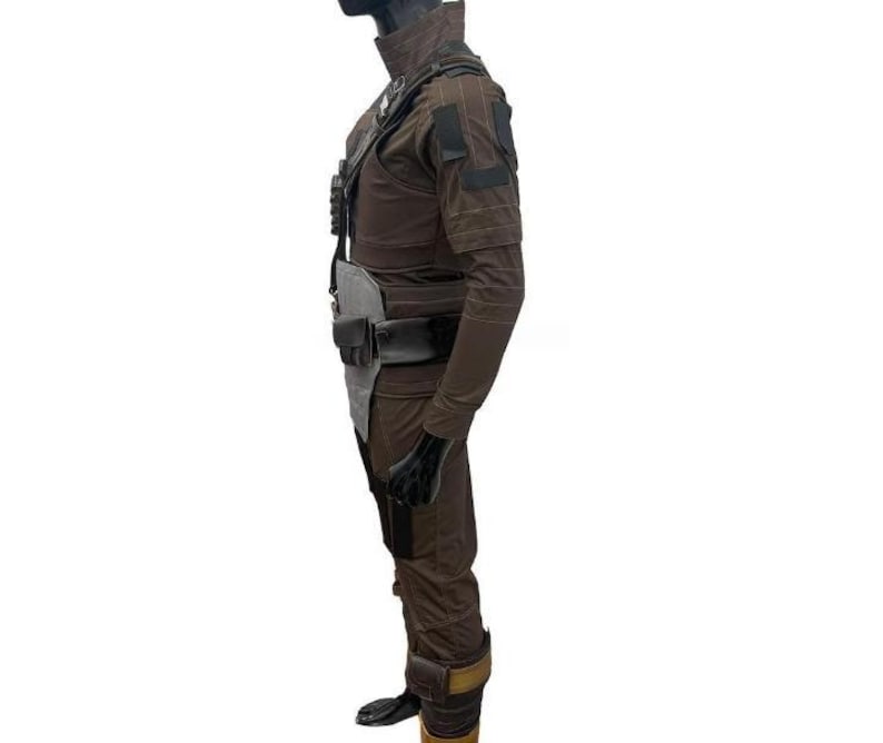 May include: A brown and black costume with a high collar, shoulder pads, and multiple pockets. The outfit includes a belt, pouches, and gloves. The costume is displayed on a mannequin.