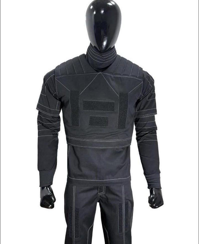 May include: A black tactical long-sleeve shirt and matching pants set featuring a high collar, padded shoulder panels, and white contrast stitching throughout. The shirt includes rectangular hook-and-loop fastener patches on the chest.