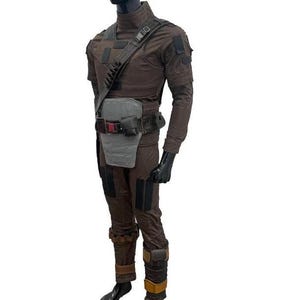 May include: A brown tactical jumpsuit with a chest rig, belt, and shoulder strap. The outfit includes a grey chest plate, black gloves, and brown boots. The mannequin is on a white background.