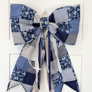 May include: A large decorative bow made from a patchwork of blue, white, and grey fabrics. The fabric features various patterns including stripes, polka dots, and the Utah State University logo with the text Utah State University and Aggies.