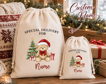 Könnte beinhalten: Zwei beige Kordelzugbeutel aus Segeltuch mit einer weihnachtlichen Illustration eines Teddybären mit Weihnachtsmütze, einem geschmückten Baum und Geschenkkartons. Der Text lautet SPECIAL DELIVERY FOR und Name in roter Schrift.