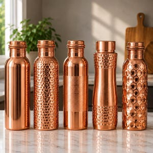 May include: Five cylindrical copper water bottles standing in a row. The first is smooth, the second has a hammered texture, the third features horizontal brushed bands, the fourth has a hammered top and base, and the fifth has a circular pattern.