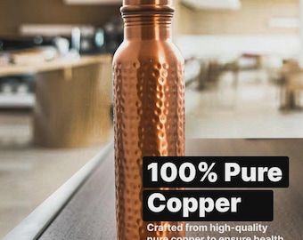 May include: A copper water bottle with a textured finish and a screw-on lid. The bottle is made of 100% pure copper, designed for health and durability. The cylindrical bottle stands on a wooden surface. The bottle is approximately 25 cm tall.